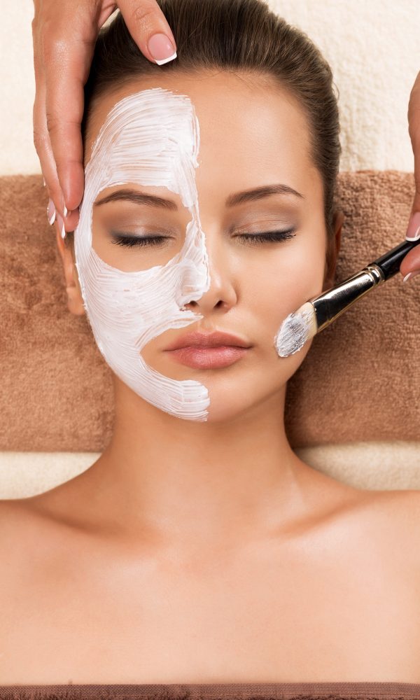 Woman having a facial cosmetic mask at spa salon.